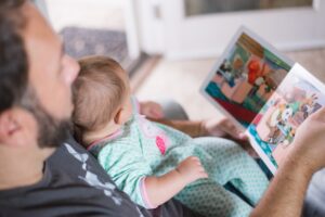 A father reading a colourful book to his baby