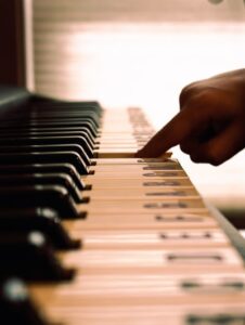 A person pressing a piano key with the notes written on the keys