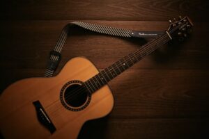 An acoustic guitar resting on a hardwood floor