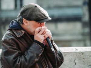 A man playing the harmonica in the public into a microphone