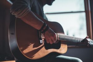 A man playing his acoustic guitar in a bright room