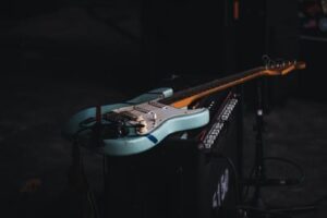 A Fender Stratocaster blue guitar resting on top of an amplifier 