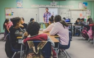 A full traditional classroom with students, a teacher and a whiteboard