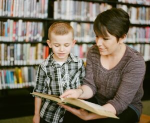 A mother teaching her son to read in a library