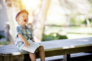 A child laughing while reading outside