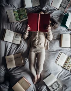 A child reading in bed surrounding by a circle of books