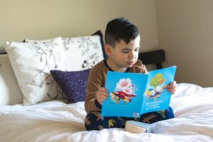 A child reading a book on a bed