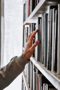 A person selecting a book from a bookshelf