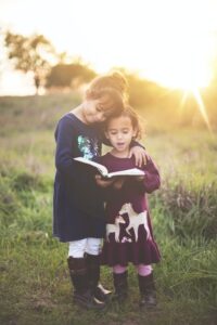 Two children reading outside together