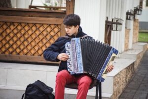 A young boy playing the Accordion outside