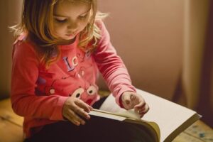 A child reading a book in her room