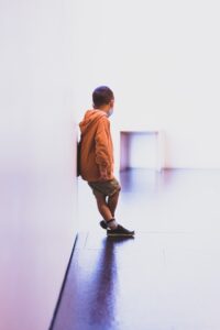 A child standing against a wall in a bright white room