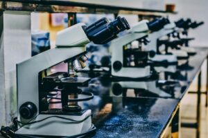 A series of microscopes on a table in a school lab