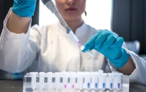 A laboratory worker putting chemicals into testubes