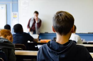 A class facing a teacher by a whiteboard