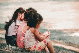 Three children sitting on a beach together