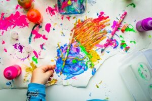A child painting on a table with many colours